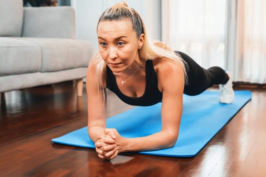 Athletic and sporty senior woman planking on fitness exercising mat at home exercise as concept of healthy fit body lifestyle after retirement. Clout