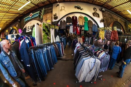 London, United Kingdom - March 31, 2007: Extreme wide angle (fisheye) photo, unknown shoppers checking clothes in one of many stalls at Camden Lock, famous flea market in UK capital.