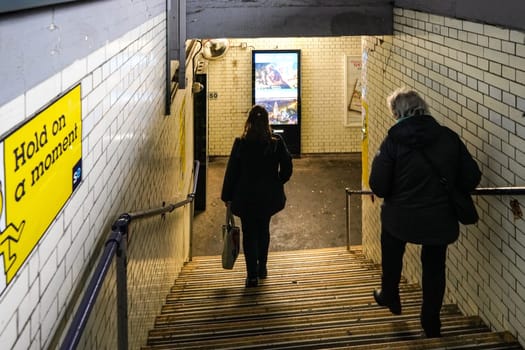 London, United Kingdom - February 01, 2019: Passengers walking down the stairs at pedestrian subway leading to other platform at Lewisham station.