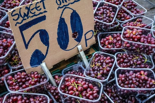 Small plastic boxes with red grapes displayed on food market at Lewisham, London