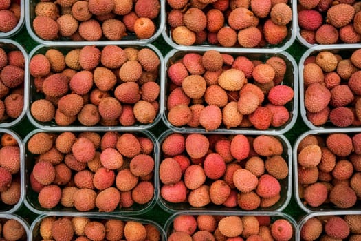 Overhead shot - lychee fruits in small plastic boxes, displayed on food market at Lewisham, London