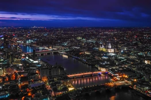 Aerial view of north east part of London, in evening. St Pauls Cathedral visible over river Thames.