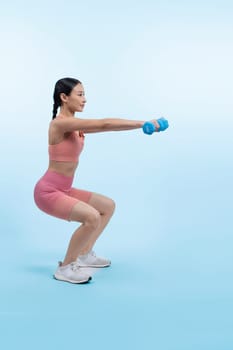 Vigorous energetic woman doing dumbbell weight lifting exercise on isolated background. Young athletic asian woman strength and endurance training session as body workout routine.