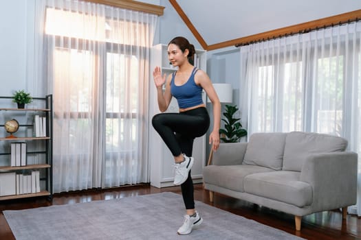 Energetic and strong athletic asian woman running in place at her home. Pursuit of fit physique and commitment to healthy lifestyle with home workout and training. Vigorous