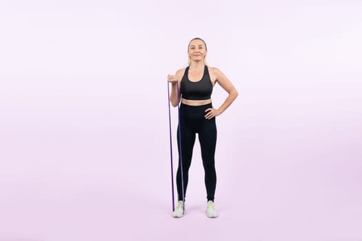 Full body length shot athletic and sporty senior woman with fitness resistance band on isolated background. Healthy active physique and body care lifestyle after retirement. Clout