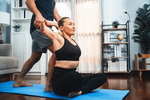 Happy active senior couple in sportswear being supportive and assist on yoga posture together at home. Healthy senior man and woman lifestyle with yoga exercise. Clout