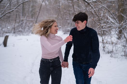 A young couple walks in the park in winter without jackets