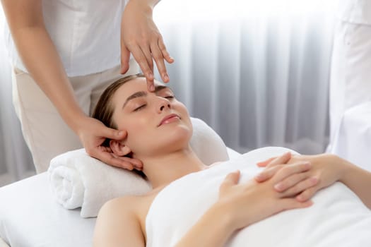 Caucasian woman enjoying relaxing anti-stress head massage and pampering facial beauty skin recreation leisure in dayspa modern light ambient at luxury resort or hotel spa salon. Quiescent