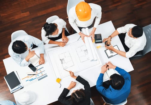 Top view banner of diverse group of civil engineer and client working together on architectural project, reviewing construction plan and building blueprint at meeting table. Prudent