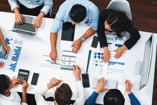 Top view analyst team utilizing BI Fintech to analyze financial data at table in meeting room. Analytic BI dashboard power on paper for business insight and strategic marketing planning. Prudent