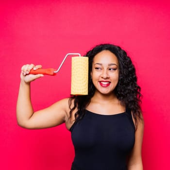 Happy young African woman with paintroller, toothy smile during home renovations