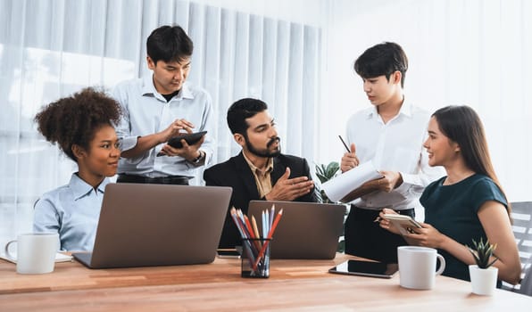 Happy diverse business people work together, discussing in corporate office. Professional and diversity teamwork discuss business plan on desk with laptop. Modern multicultural office worker. Concord