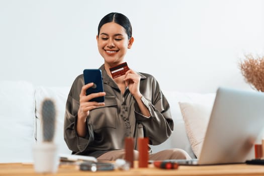 Young happy Asian woman buy product by online shopping at home while ordering items from the internet with credit card online payment protected by uttermost cyber security from online store platform