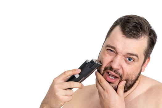 Isolated shot of a young man grooming with an electric razor on a white background. The man appears focused and the image reflects personal care and grooming.