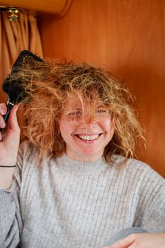 In this image, a young girl is delicately and meticulously combing through severely tangled hair, demonstrating patience and gentle care in addressing the challenging knots.