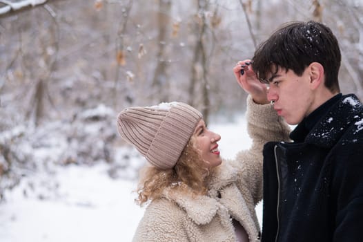 A young couple walks in the park in winter. Guy and girl fooling around on the street