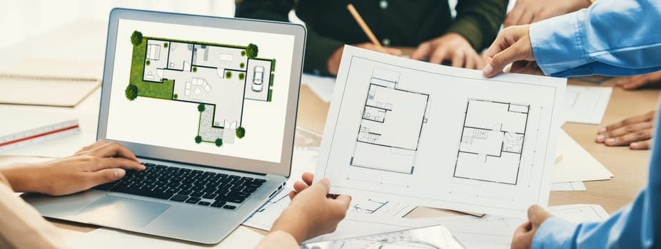 Professional architect decide the blueprint for eco-friendly house during discussion about changing blueprint plan at meeting table with architectural document scatter around. Closeup. Delineation