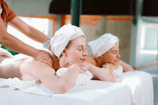 Couple of beautiful young woman lie on white spa bed during having back massage. Attractive caucasian woman having back massage at traditional spa room. Relaxing and healthy concept Tranquility.