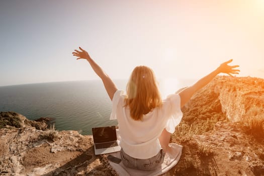 Woman sea laptop. Business woman in yellow hat working on laptop by sea. Close up on hands of pretty lady typing on computer outdoors summer day. Freelance, digital nomad, travel and holidays concept.