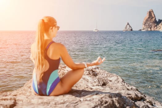 Woman sea yoga. Back view of free calm happy satisfied woman with long hair standing on top rock with yoga position against of sky by the sea. Healthy lifestyle outdoors in nature, fitness concept.