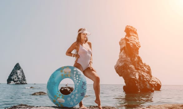 Woman summer sea. Happy woman swimming with inflatable donut on the beach in summer sunny day, surrounded by volcanic mountains. Summer vacation concept