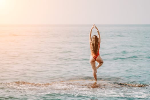 Woman sea yoga. Back view of free calm happy satisfied woman with long hair standing on top rock with yoga position against of sky by the sea. Healthy lifestyle outdoors in nature, fitness concept.