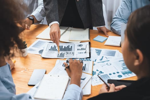 Multiracial analyst team use BI dashboard data to analyze financial report on meeting table. Group of diverse business people utilize data analysis by FIntech for business marketing decision. Concord