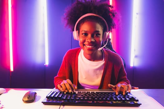 Gaming streamer, African girl playing online fighting with Esport skilled team wearing headphones in neon color lighting room. Talking other players planing strategies to win competitors. Tastemaker.