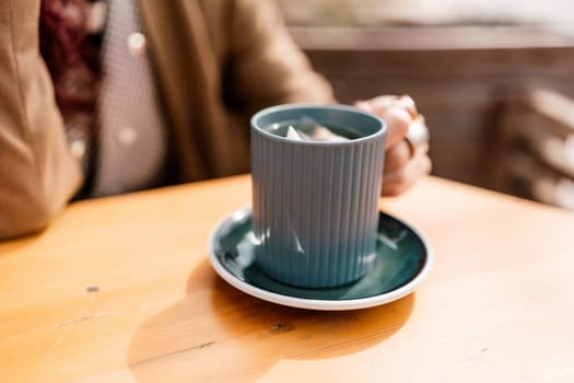 woman holding a cup of hot cappuccino coffee in a cafe on the street, rings on her fingers