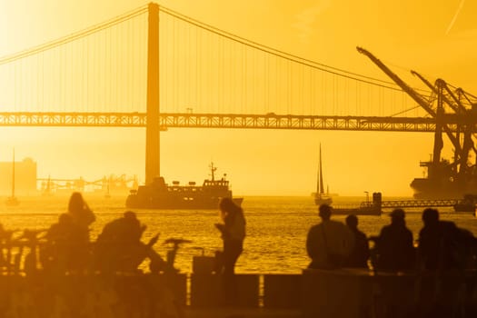 A group of people standing on a pier next to a bridge