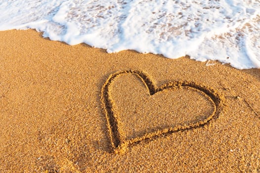 Heart drawn in the sand on the beach at sunset. Heart shape. Heart symbol. Love. Sea foam.