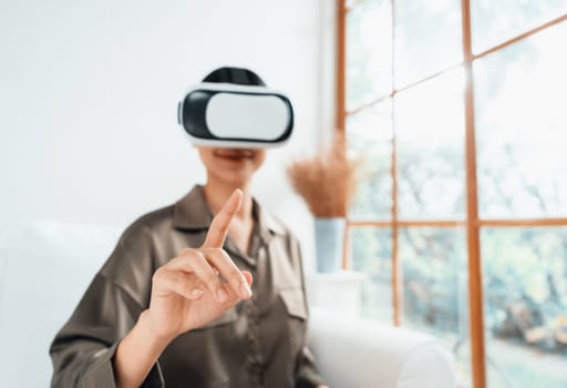 Young woman using virtual reality VR goggle at home for uttermost online shopping experience. The virtual reality VR innovation optimized for digital entertainment lifestyle.