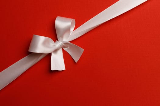 White gift bow on red background holiday gift concept