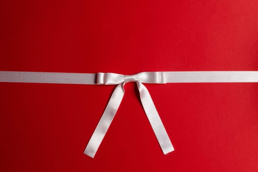 White gift bow on red background copy space for text
