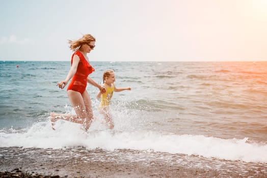 Happy loving family mother and daughter having fun together on the beach. Mum playing with her kid in holiday vacation next to the ocean - Family lifestyle and love concept.