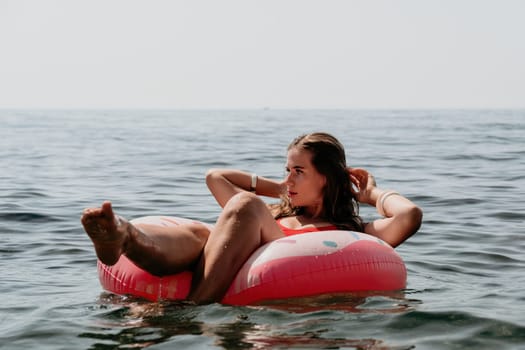 Woman summer sea. Happy woman swimming with inflatable donut on the beach in summer sunny day, surrounded by volcanic mountains. Summer vacation concept