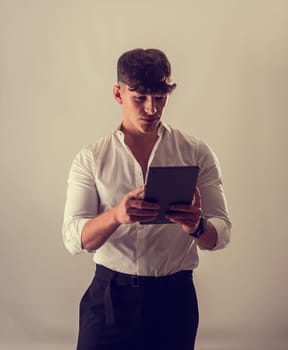 A man in a white shirt is looking at a tablet. A Curious Man in a Crisp White Shirt Engrossed in a Technological Tablet Computer