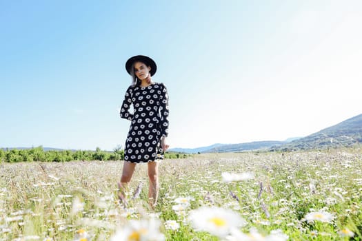 woman in hat walk in a field of daisies flowers