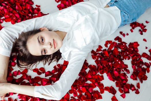 a woman lies in red rose petals romance holiday