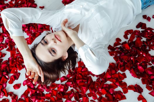 a woman lies in red rose petals romance holiday