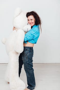 woman stands with a large soft teddy bear toy
