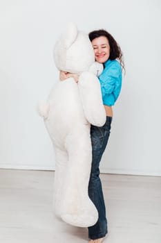 woman stands with a large soft teddy bear toy