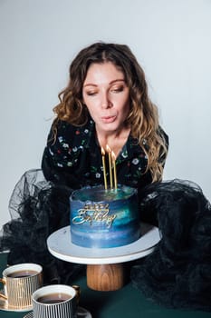 woman blows out candles on cake two cups of coffee delicious dessert sweets