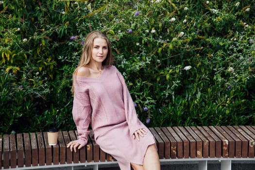 blonde woman sitting on bench by green bushes