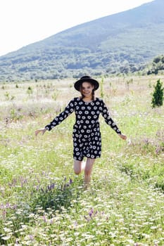 woman in a hat runs through a field of flowers in nature