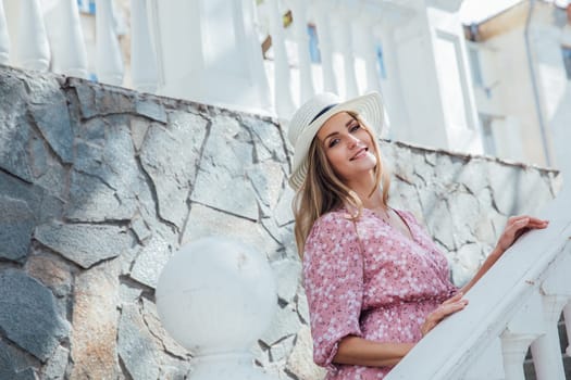 beautiful blonde in a glab walk on the street near the white railing near the building