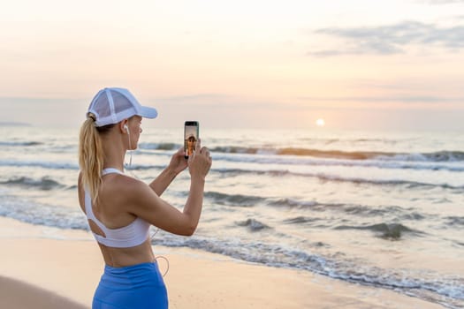 girl runner runs along the beach in sportswear. the girl takes a photo of the sunrise at sea before jogging, there is a place for an inscription. High quality photo