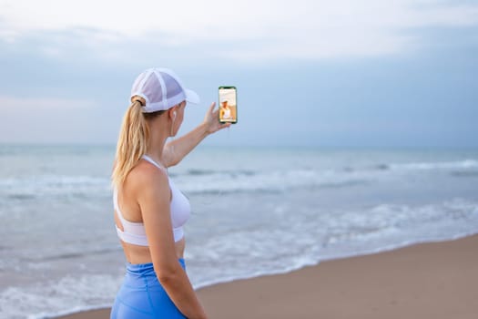 girl runner runs along the beach in sportswear. girl takes a selfie on the seashore before jogging. High quality photo