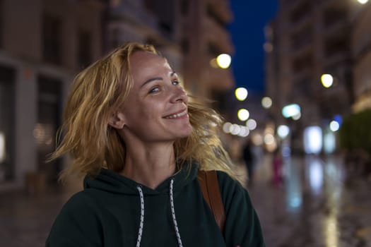 Beautiful girl smiles in the evening, the girl has blond hair, the girl shakes her head, selective focus. High quality photo