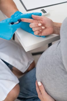 The doctor checks the blood sugar level of a pregnant patient. Gestational diabetes. Vertical photo